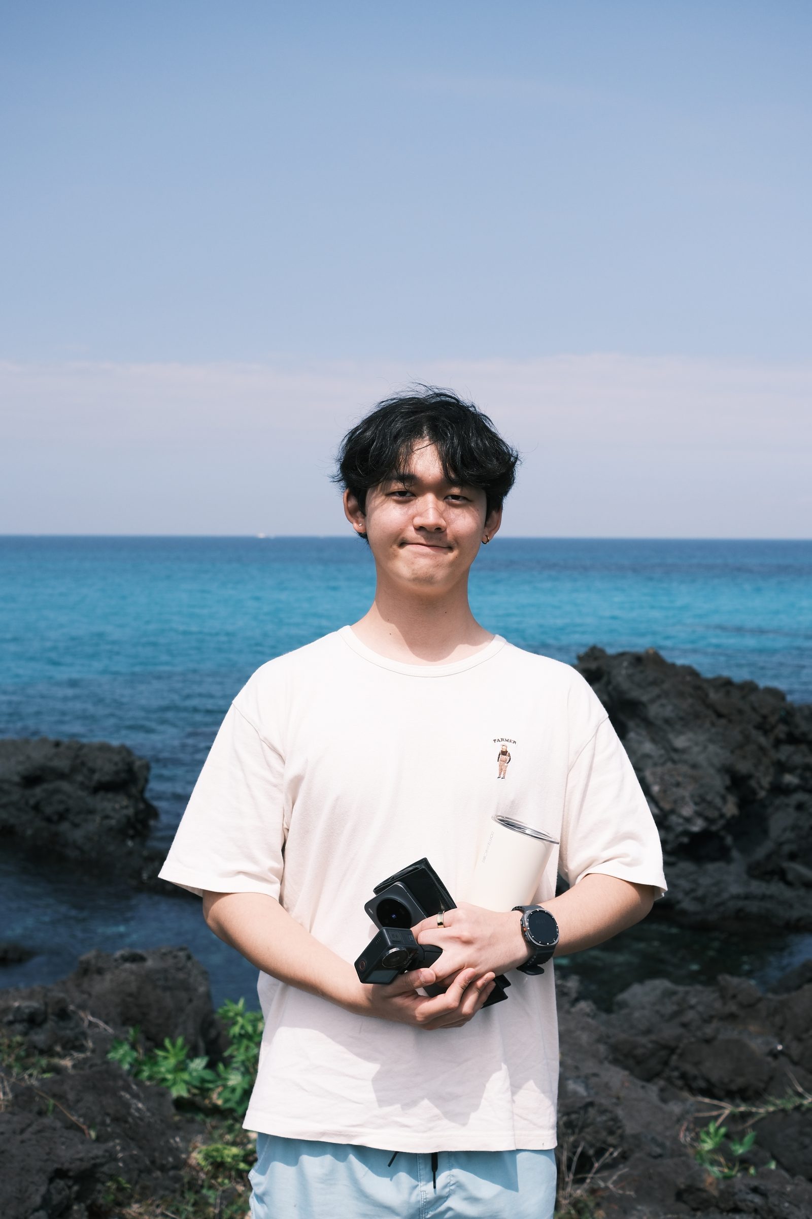 済州の海を背にカメラを抱えて立つ Paul Ryosuke